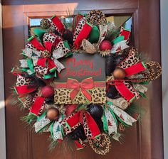 a leopard print christmas wreath with red, green and black bows on the front door