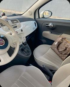 the interior of a small car with a handbag on the steering wheel