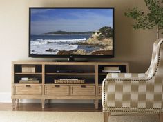 a flat screen tv sitting on top of a wooden entertainment center next to a chair