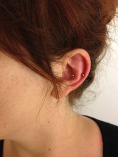 a close up of a person wearing a pair of ear piercings on their ears