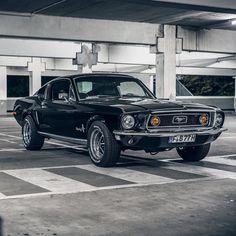 an old black muscle car parked in a parking garage