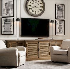 a living room with two chairs and a large clock on the wall above it's entertainment center