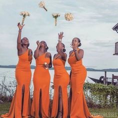 three women in orange dresses are throwing flowers into the air