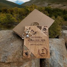 a wedding card on top of a rock in the mountains