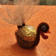 a small bird made out of gold foil on an orange tablecloth with glitters