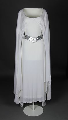 a white dress with long sleeves and a belt on display in front of a black background