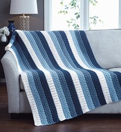 a blue and white blanket sitting on top of a couch next to a window in a living room