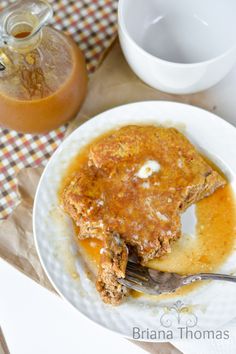 a white plate topped with food next to a cup of tea and a jar of syrup