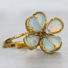 A beautiful and pear shapped opal ring, featuring a romantic side profile of a split shank with a textured finnish. At it's center is one bright white diamond measuring to 2.1mm. This authentic antique ring is crafted in 14k yellow gold shaped in as flower. Finger size 5.5. Details: Size: 5.5 14k Yellow Gold 6 Pear Opals Measurement: 6.5x5x2mm Diamonds 1 Round Diamond Measurement: 2.1mm Total carat weight: 0.035cts Prong Set Textured Finish only available at Burdeen's Jewelry. We have many uniqu Fine Jewelry Pear-shaped Opal Ring, Opal Ring With Rose Cut Diamonds For Anniversary, Anniversary Opal Ring With Rose Cut Diamonds, Teardrop Diamond Opal Ring For Anniversary, Fine Jewelry Teardrop Opal Ring For Anniversary, Yellow Gold Pear-shaped Opal Ring, Elegant Pear-shaped Opal Ring, Fine Jewelry Opal Rings In Pear Shape, Pear-shaped Opal Rings Fine Jewelry