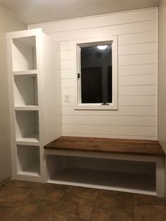 an empty room with some shelves and a mirror on the wall next to a window