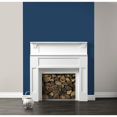 a white fireplace with blue walls and wood stacked on it's sides in a living room