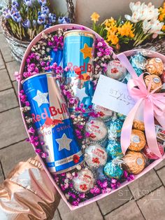 a pink heart shaped box filled with candy and candies next to some flowers on the ground