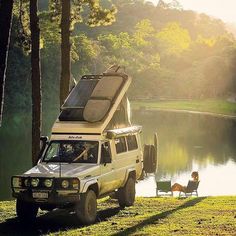 an suv parked next to a body of water with a camper on it's roof