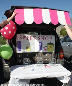 two people standing in front of a car with a sweet shop sign on the back