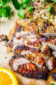 grilled pork chops on a cutting board with orange slices and parsley garnish