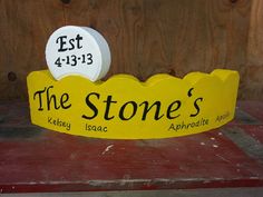 a yellow sign that says the stone's on top of a red table next to a wooden wall