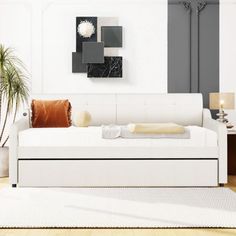 a living room with a white couch and some plants on the side of the wall