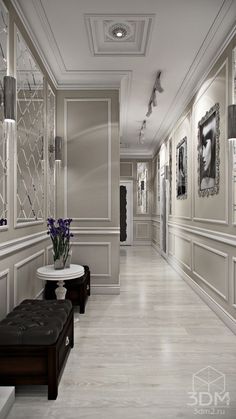 a long hallway with white walls and wooden floors, decorated with framed pictures on the wall