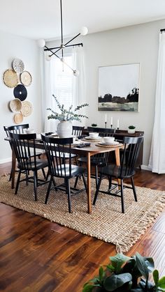 the dining room table is set with black chairs and placemats on top of a rug