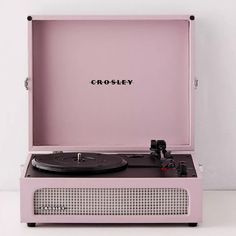 a pink record player sitting on top of a white table with the word crosley printed on it