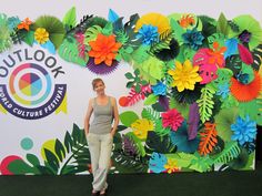 a woman standing in front of a colorful wall with paper flowers on it and the words outlook