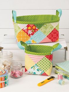 two quilted baskets sitting on top of a table next to scissors and other sewing supplies