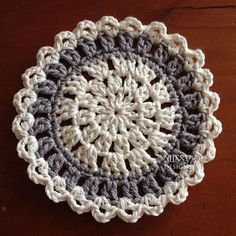 a crocheted doily on a wooden table with a brown and white background