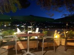 an outdoor table with chairs and umbrellas at night