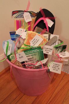 a pink bucket filled with lots of different items on top of a hard wood floor