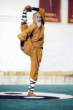 an old man is doing karate on a mat with his legs up in the air