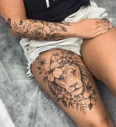 a woman with a lion tattoo on her thigh, sitting in front of a bed