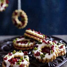 cookies with white icing and cranberry toppings are on a black plate