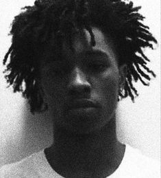 a black and white photo of a young man with dreadlocks on his head