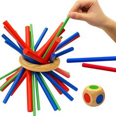 a hand is holding a wooden toy with colored sticks in it and an object next to it