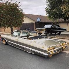 an old car parked on the side of the road in front of a house with two older cars behind it