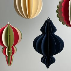 three paper lanterns hanging from the ceiling in different shapes and sizes, each with an ornament shaped like a flower