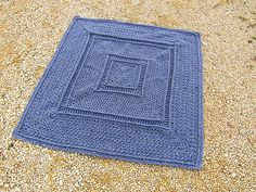 a blue crocheted blanket laying on the ground