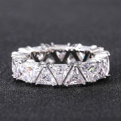 a wedding ring with three princess cut diamonds on it's sides and four prongs in the middle