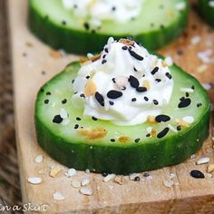 cucumber slices topped with whipped cream and sprinkles on a cutting board