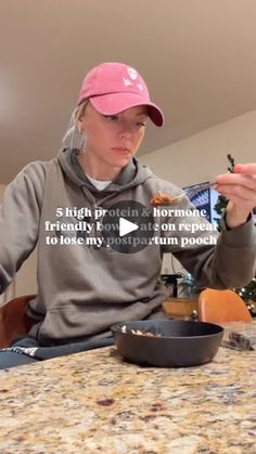 a woman sitting at a table eating food from a black pan on top of it