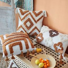 pillows and fruit on a wicker table