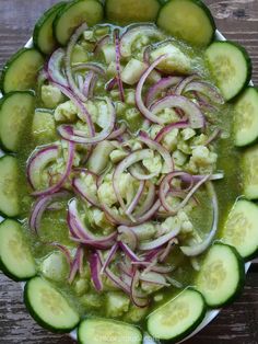 cucumbers and onions are mixed together in a green sauce on a white plate