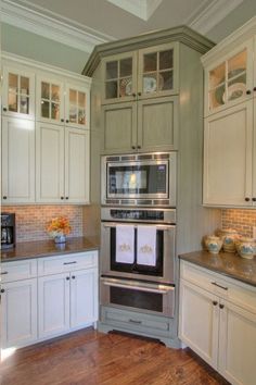 a kitchen with white cabinets and stainless steel appliances in the center, along with wood flooring