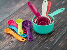 colorful measuring cups and spoons sitting on a wooden table next to eachother