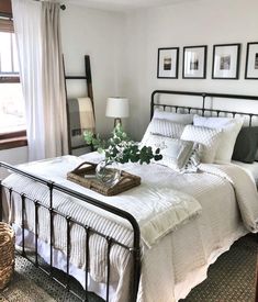 a bed with white sheets and pillows in a bedroom next to a window filled with pictures