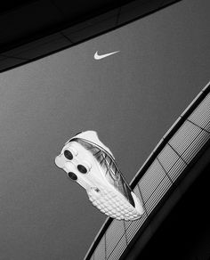 a white nike shoe hanging off the side of a building in front of a black and white sky