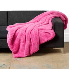 a black couch with a pink blanket on it