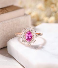 a pink diamond ring sitting on top of a white box