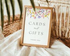 a sign that says cards and gifts on it next to a basket full of flowers