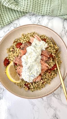 a white plate topped with salmon and lentulas next to a fork on a marble table